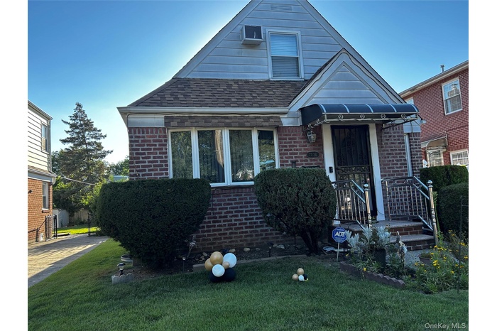 Bungalow-style home with brick siding, roof with shingles, and a front yard