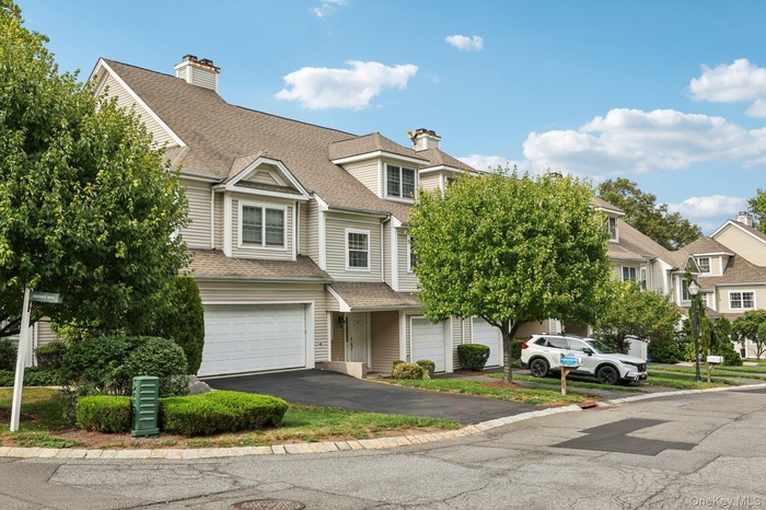 View of front facade featuring asphalt driveway, roof with shingles, an attached garage, and a residential view