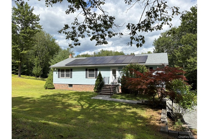 View of front of home featuring a front lawn, roof mounted solar panels, and a chimney