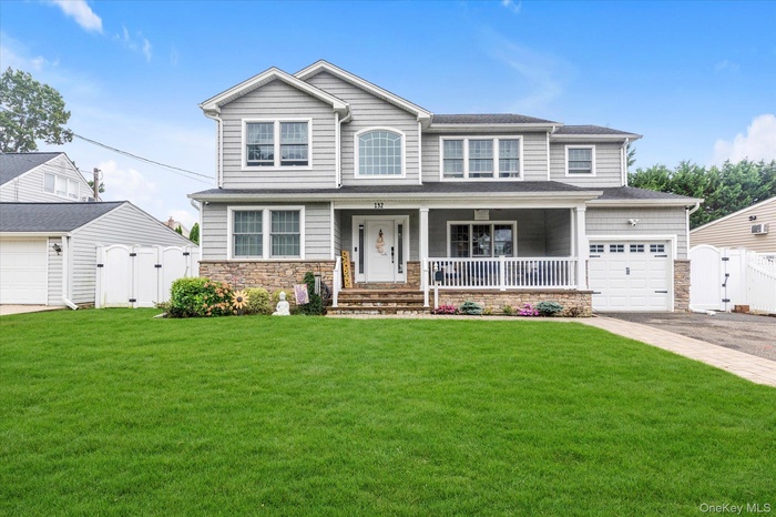 View of the front of the house featuring  stone siding, a large porch, driveway, and an attached garage