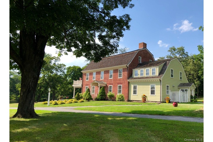 View of front of home with a gambrel roof, a front yard, a chimney, and roof with shingles