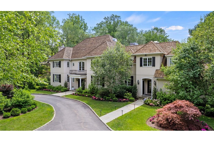 View of front of house featuring stucco siding, a chimney, and a front yard