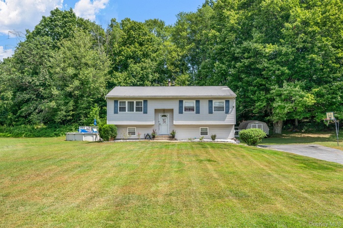 Bi-level home featuring a front yard and a storage unit