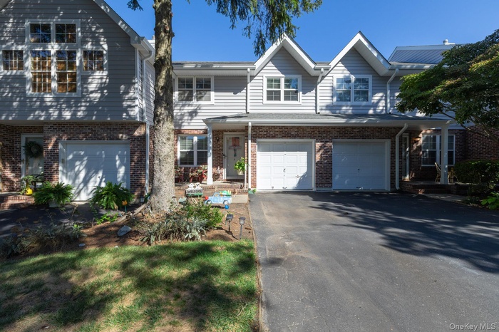 Traditional-style house with a garage, asphalt driveway, and brick siding