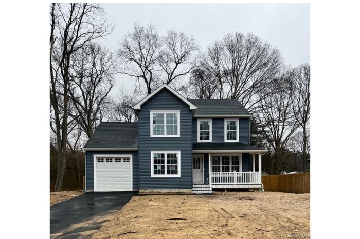 Traditional home with a garage, a porch, asphalt driveway, and a shingled roof