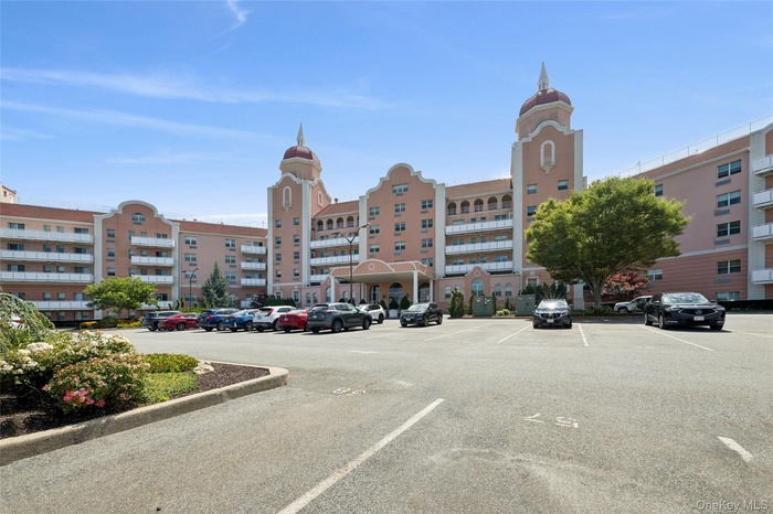 View of apartment building / complex featuring uncovered parking