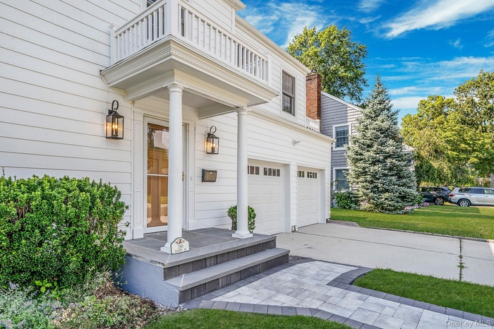 Doorway to property featuring driveway, a garage, and a lawn