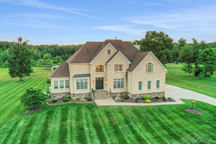 Traditional home with stone siding, a front lawn, and a shingled roof
