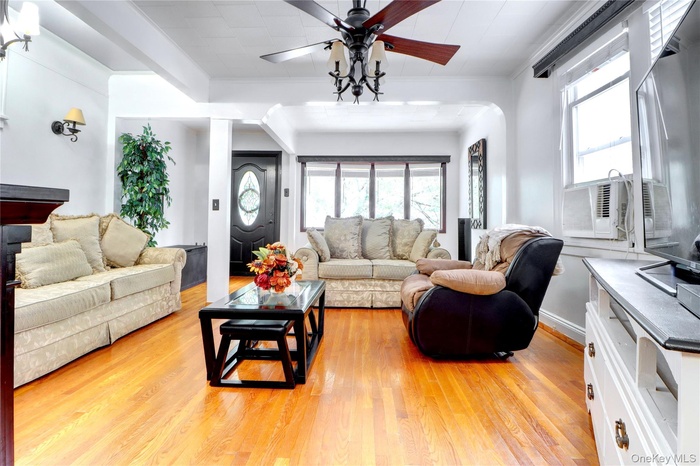Living area featuring healthy amount of natural light, light wood-style floors, a ceiling fan, crown molding, and cooling unit