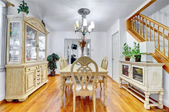 Dining area featuring light wood-type flooring, a chandelier, stairs, and crown molding