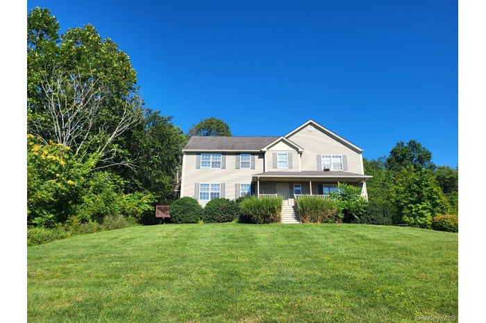 Lovely view of front of colonial style duplex with rocking chair front porch and lush front lawn~