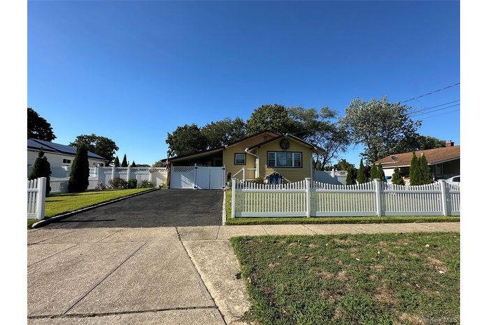View of front facade with driveway, a fenced front yard, and a gate