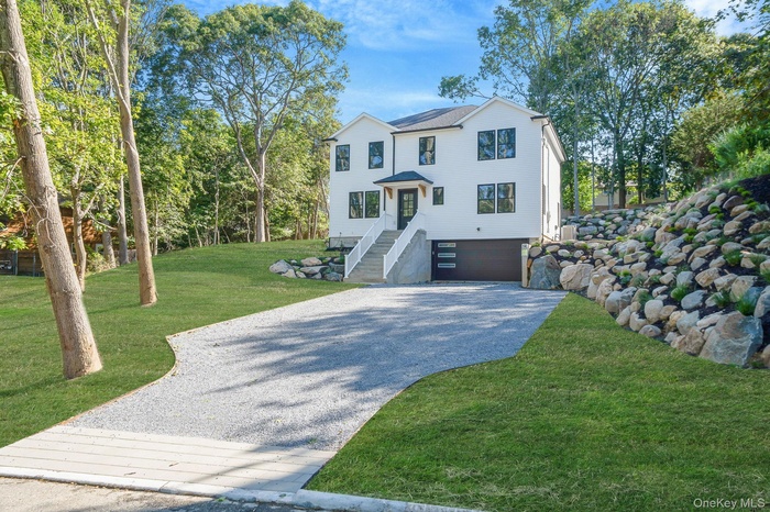 View of front of house featuring driveway, a garage, a front yard, and stairs