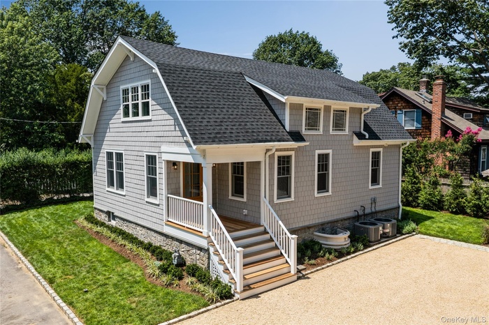 View of front of home featuring a shingled roof, a front lawn, a porch, and a gambrel roof