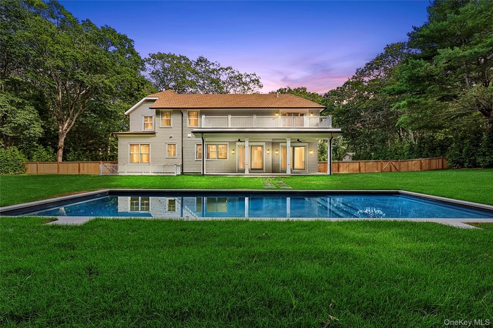 Rear view of house featuring a fenced backyard, a patio area, a balcony, and a ceiling fan