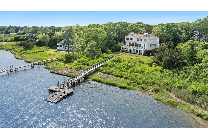Aerial view of property and surrounding area featuring a large body of water and a heavily wooded area
