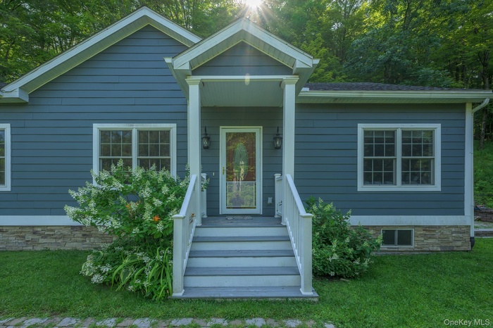 View of front facade with a porch, a front yard, and a shingled roof