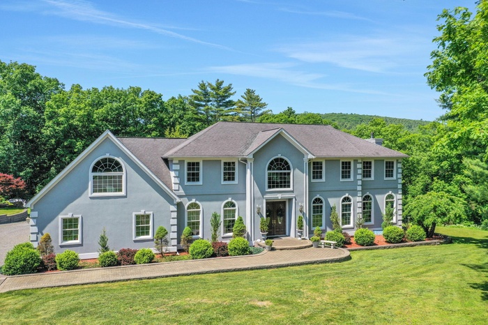 View of front facade featuring stucco siding, a front lawn, and a chimney