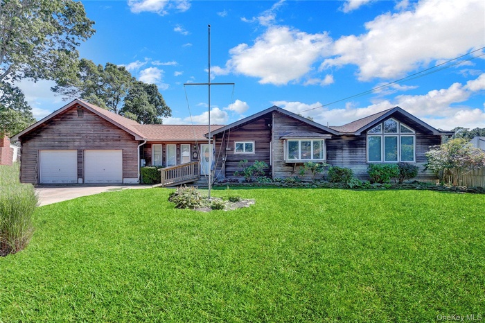 Ranch-style home featuring a garage, a front yard, and driveway