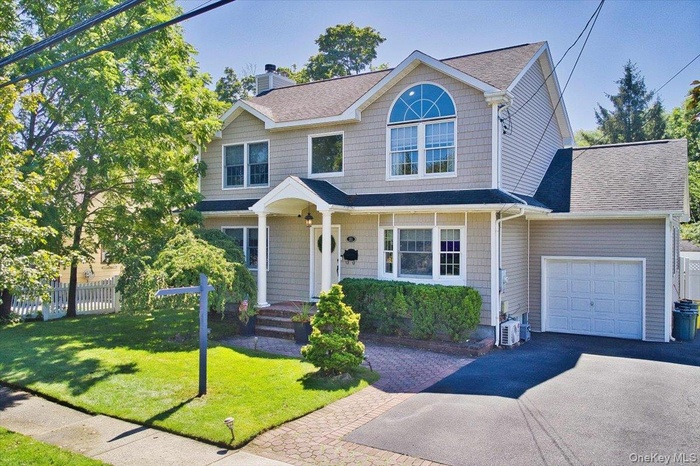 View of front of house featuring a chimney, a shingled roof, asphalt driveway, and an attached garage
