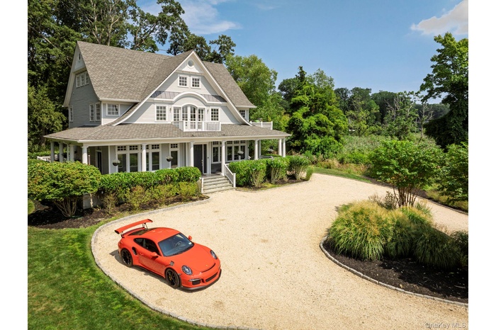Back of property featuring roof with shingles, gravel driveway, and covered porch