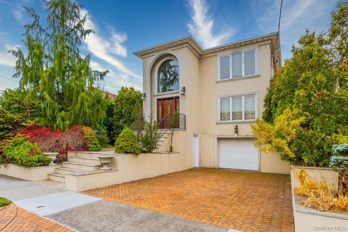 View of front of property with stucco siding, a garage, stairs, and decorative driveway