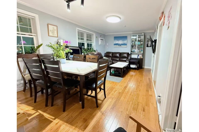 Dining room featuring ornamental molding, light wood-type flooring, and a wall unit AC