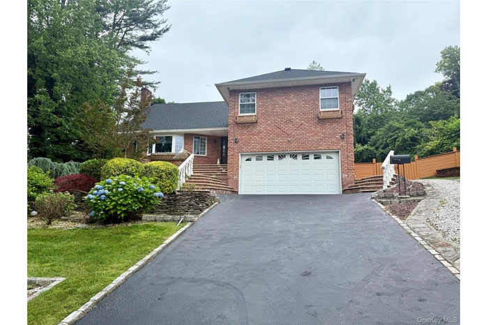 Split level home with driveway, an attached garage, and brick siding