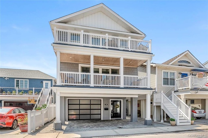 Beach home with stairway, an attached garage, decorative driveway, board and batten siding, and a balcony