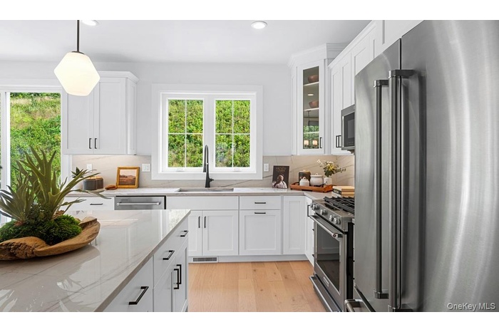Kitchen with stainless steel appliances, hanging light fixtures, white cabinets, recessed lighting, and light wood-style flooring