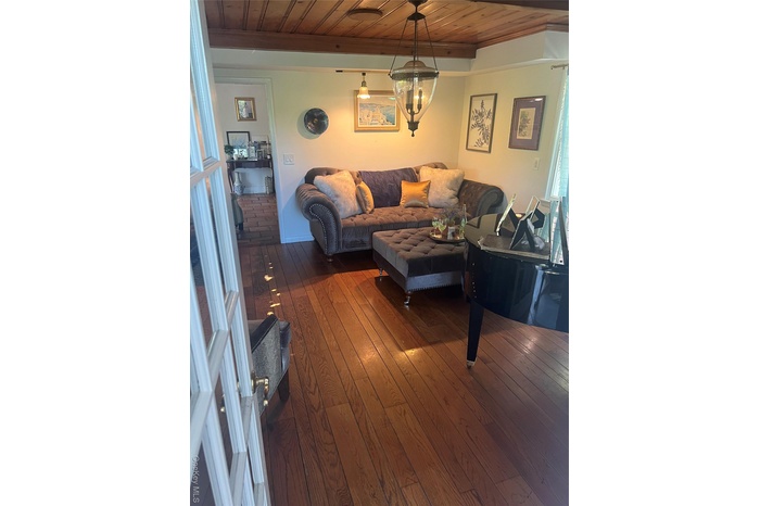 Living room featuring a wood ceiling with exposed beams and dark wood-type flooring