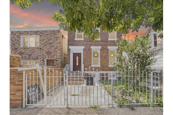 View of front of house with a fenced front yard, a gate, and brick siding