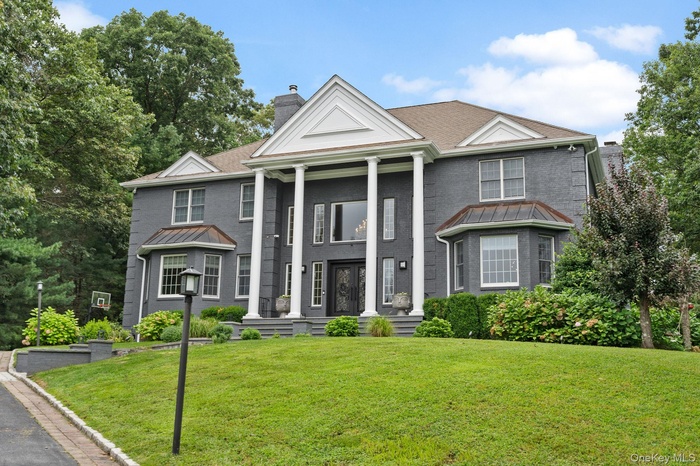 Greek revival inspired property with a chimney, a standing seam roof, a front yard, and brick siding