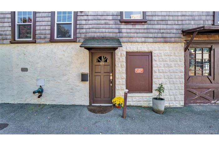 Entrance to property with stucco siding and mansard roof
