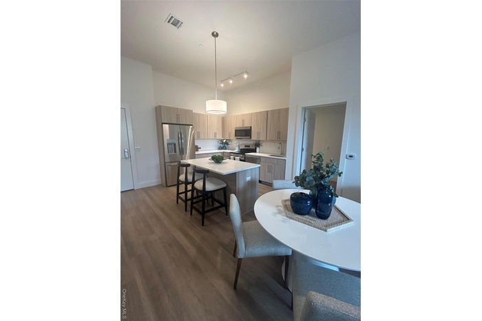 Kitchen featuring pendant lighting, refrigerator, dark wood-type flooring, a kitchen breakfast bar, and a kitchen island