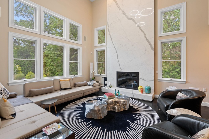 Living area with a towering ceiling, plenty of natural light, a fireplace, and wood finished floors