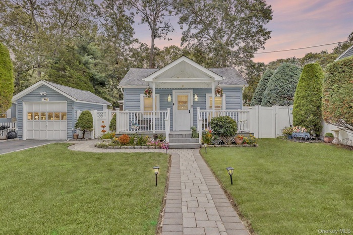 Bungalow-style house with a garage, an outdoor structure, a yard, and roof with shingles