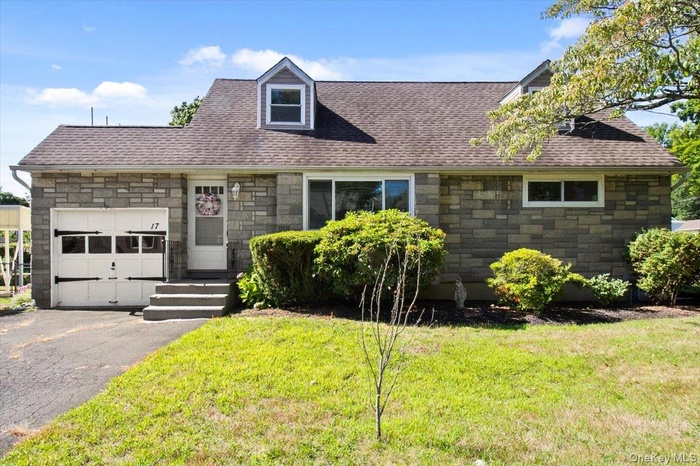 Cape cod home with a garage, stone siding, driveway, and a shingled roof