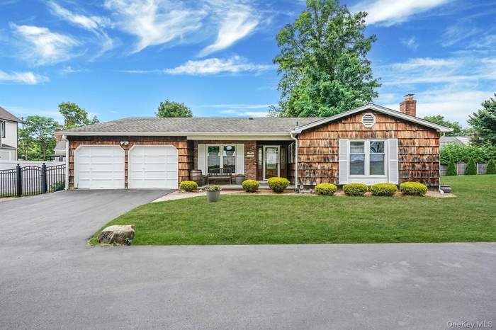 Ranch-style house featuring a garage, asphalt driveway, a porch, a shingled roof, and a chimney