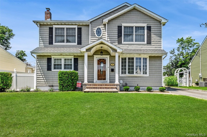 View of front of property featuring a shingled roof, a chimney, and driveway