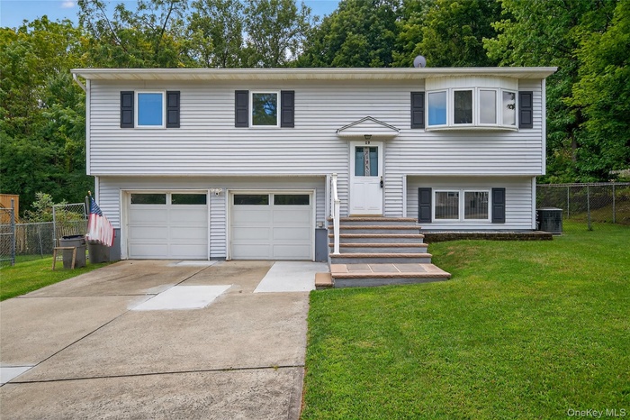 Raised ranch featuring an attached garage and driveway