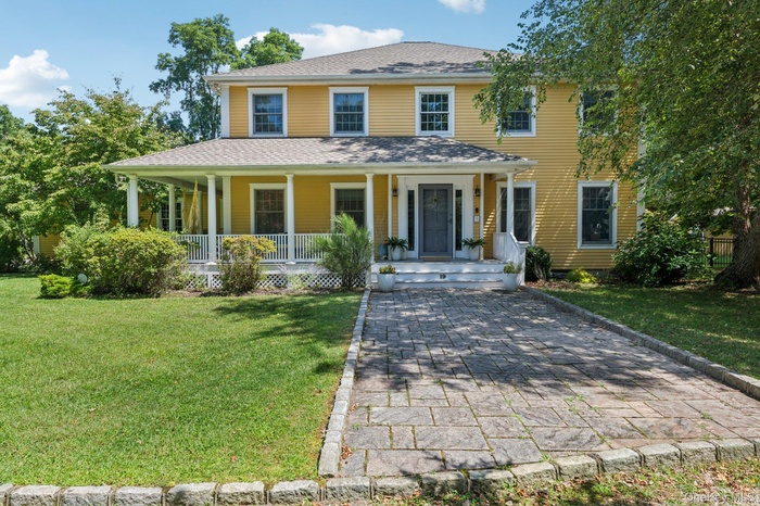 View of front facade featuring covered porch, a front lawn, and roof with shingles