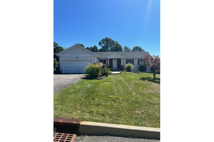Single story home featuring an attached garage, asphalt driveway, and a front lawn