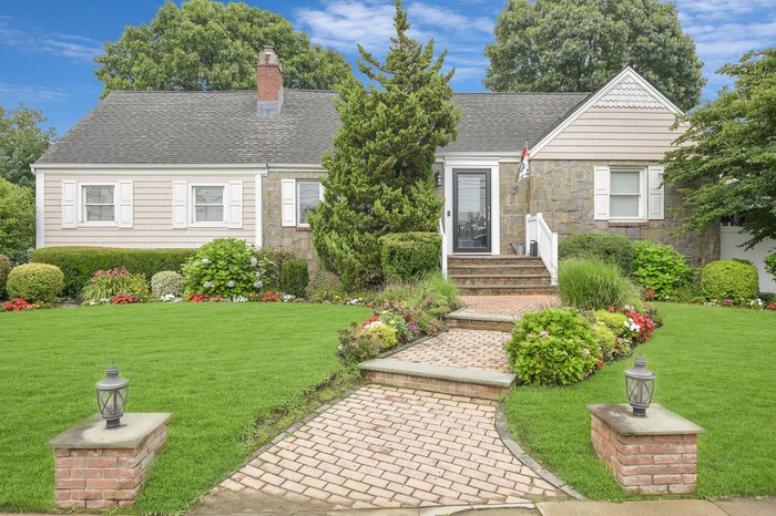 View of front of home with stone siding, a chimney, and a front yard