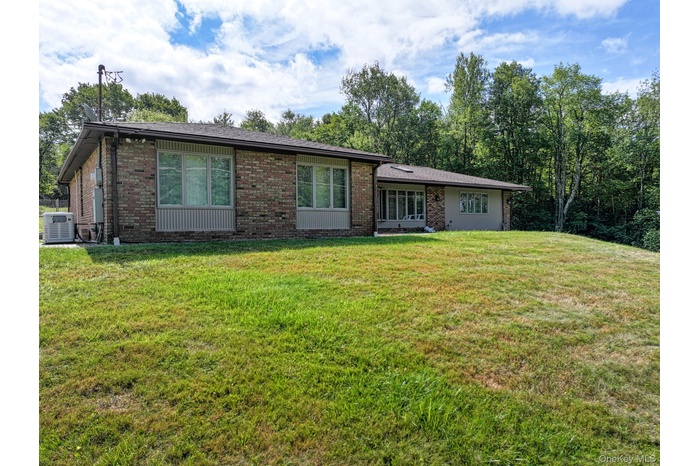 View of front of property featuring a front yard, brick siding, and a shingled roof