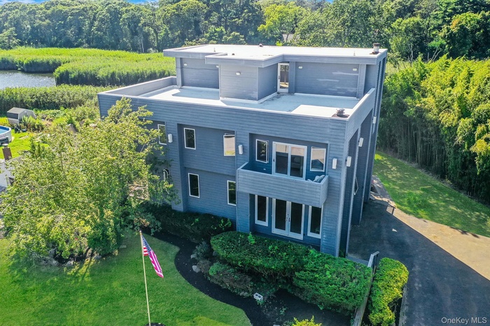View of front of house featuring asphalt driveway, a front yard, and a forest view