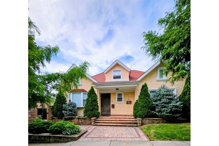 Bungalow-style home with covered porch, a shingled roof, and brick siding