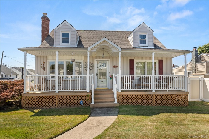 View of front of home with a porch, a chimney, a front yard, and a shingled roof