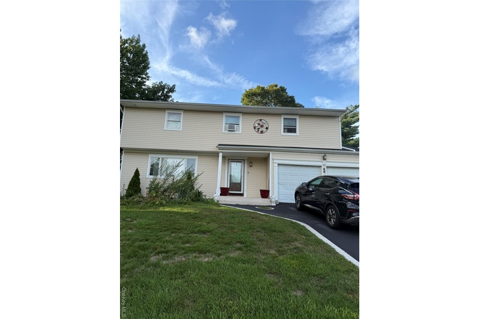 View of front of house with an attached garage, driveway, and a front lawn