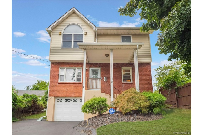 Traditional-style house featuring an attached garage, covered porch, brick siding, and  driveway